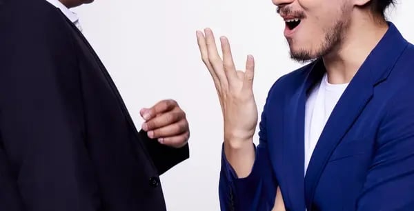 Two men facing each other - one with an excited hand gesture and facial expression